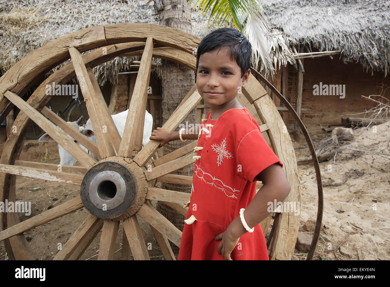 Ritratto di una giovane ragazza in piedi accanto a un carrello di legno ruota; Ratapata Village, Badamba, India Foto Stock