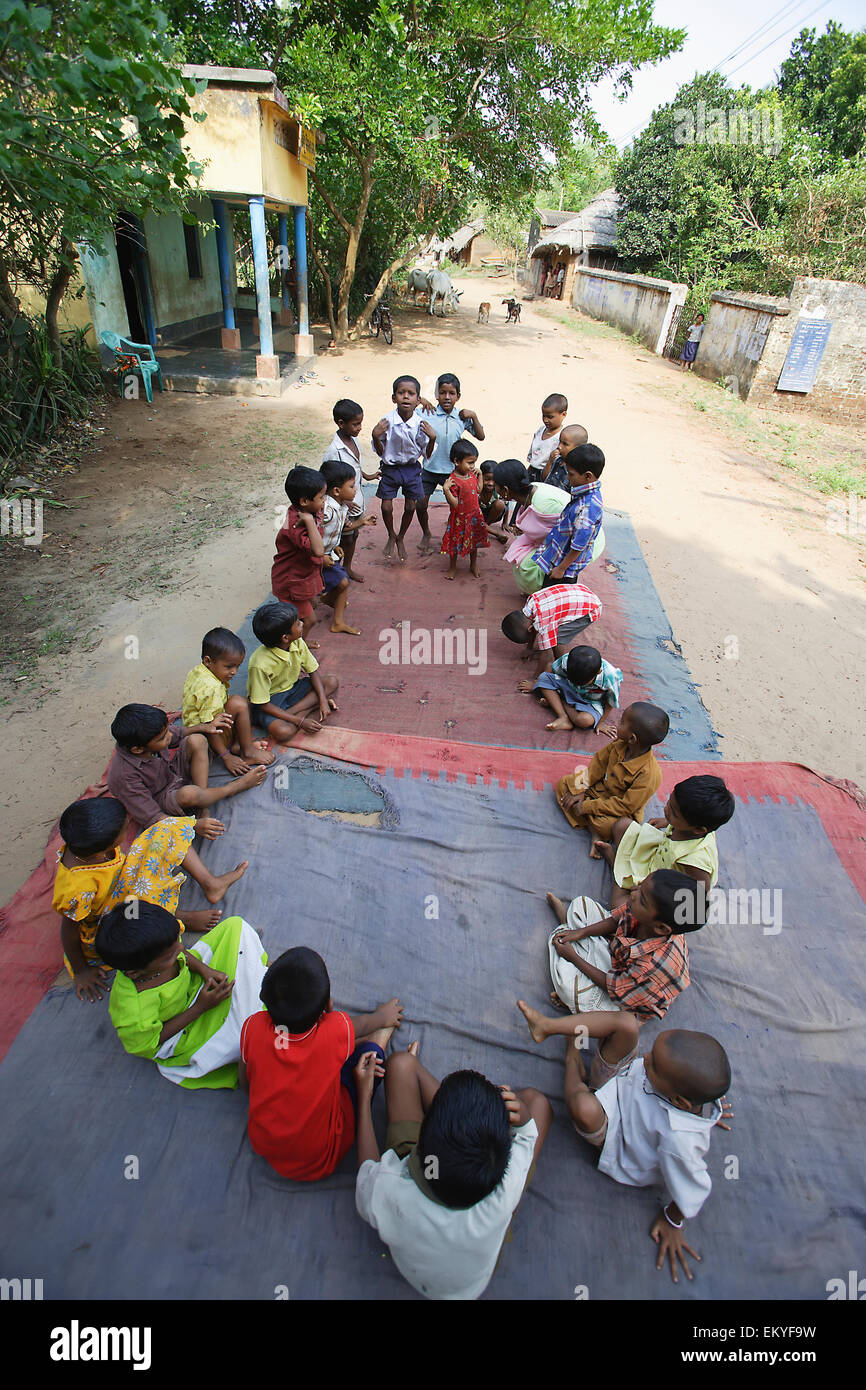 Un gruppo di studenti di scuola materna fare esercizi su un tappetino esterno; Katakpada Village, India Foto Stock