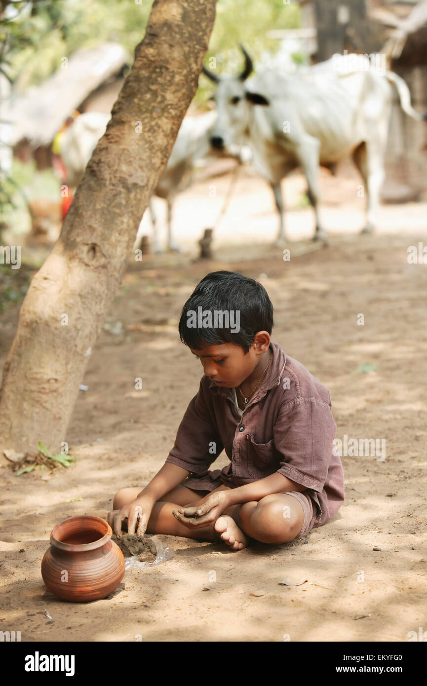 Un bambino gioca con argilla; Katakpada Village, India Foto Stock