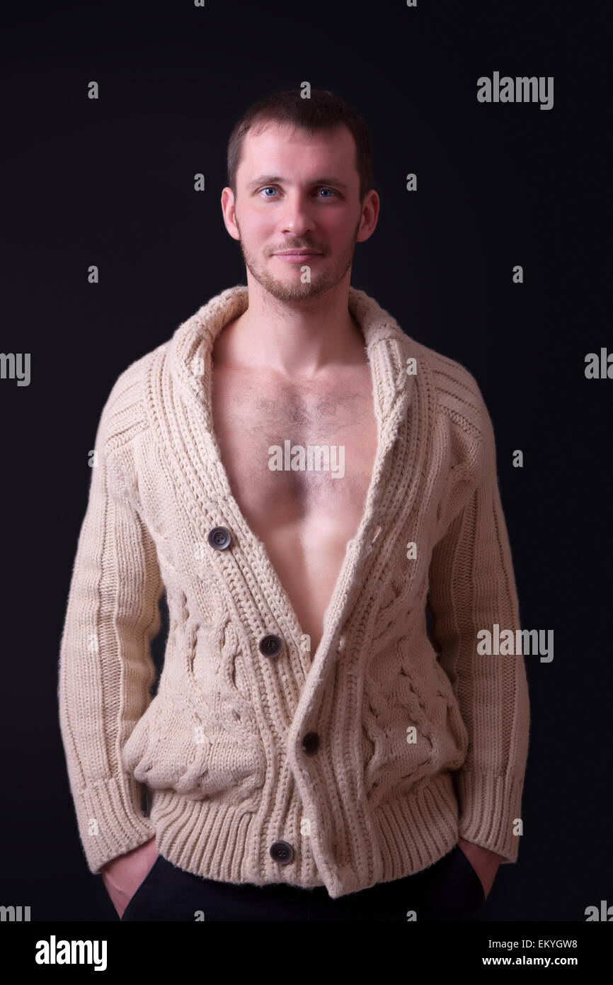 Ritratto di una giovane e bella uomo in un maglione, sfondo nero Foto Stock