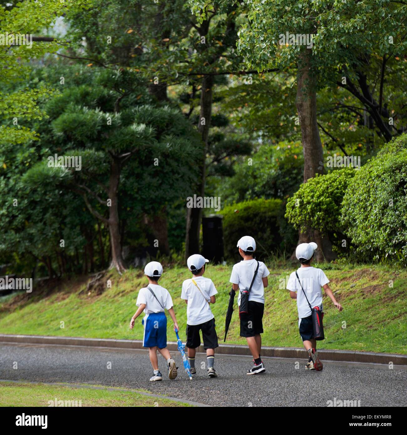 Quattro ragazzi camminando per un sentiero nel Parco della Pace; Nagasaki, Giappone Foto Stock