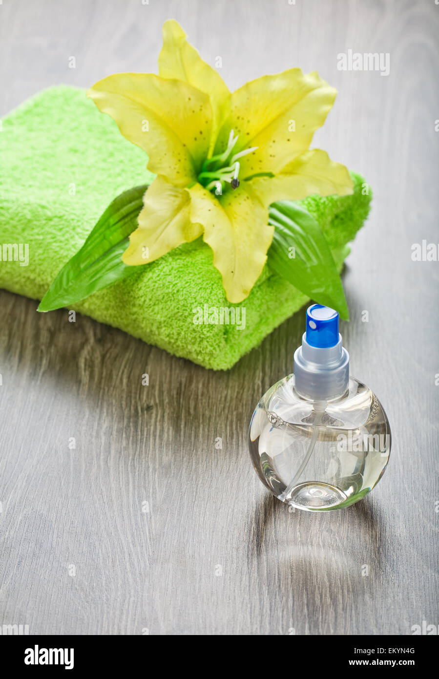 Fiore giallo su un asciugamano e bottiglia trasparente Foto Stock