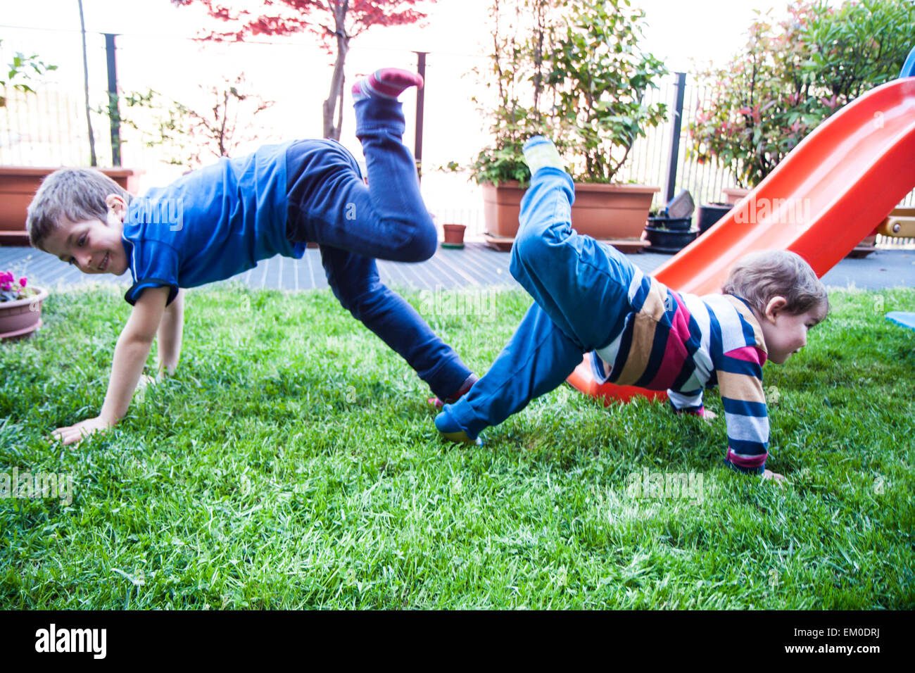 Due fratelli giochi nel giardino sulla diapositiva Foto Stock