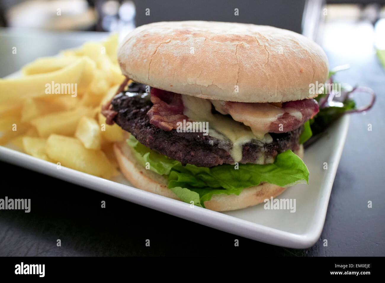 La pancetta e formaggio hamburger con patatine fritte in un gastropub Foto Stock