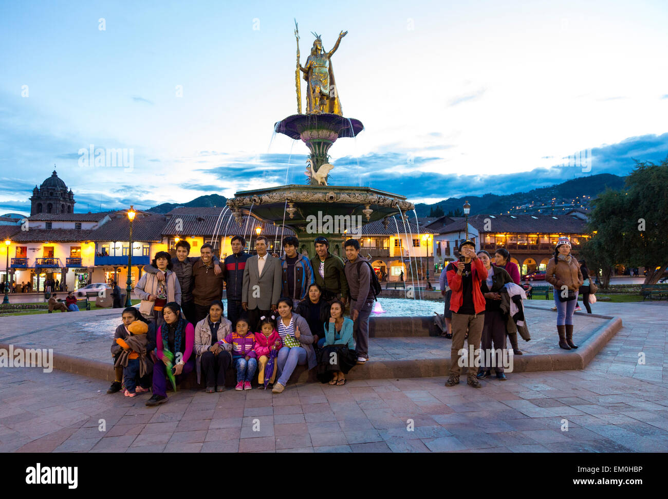 Perù Cusco. I peruviani che posano per una foto di gruppo sotto la statua del re inca Pachacutec sopra Fontana in Plaza de Armas. Foto Stock