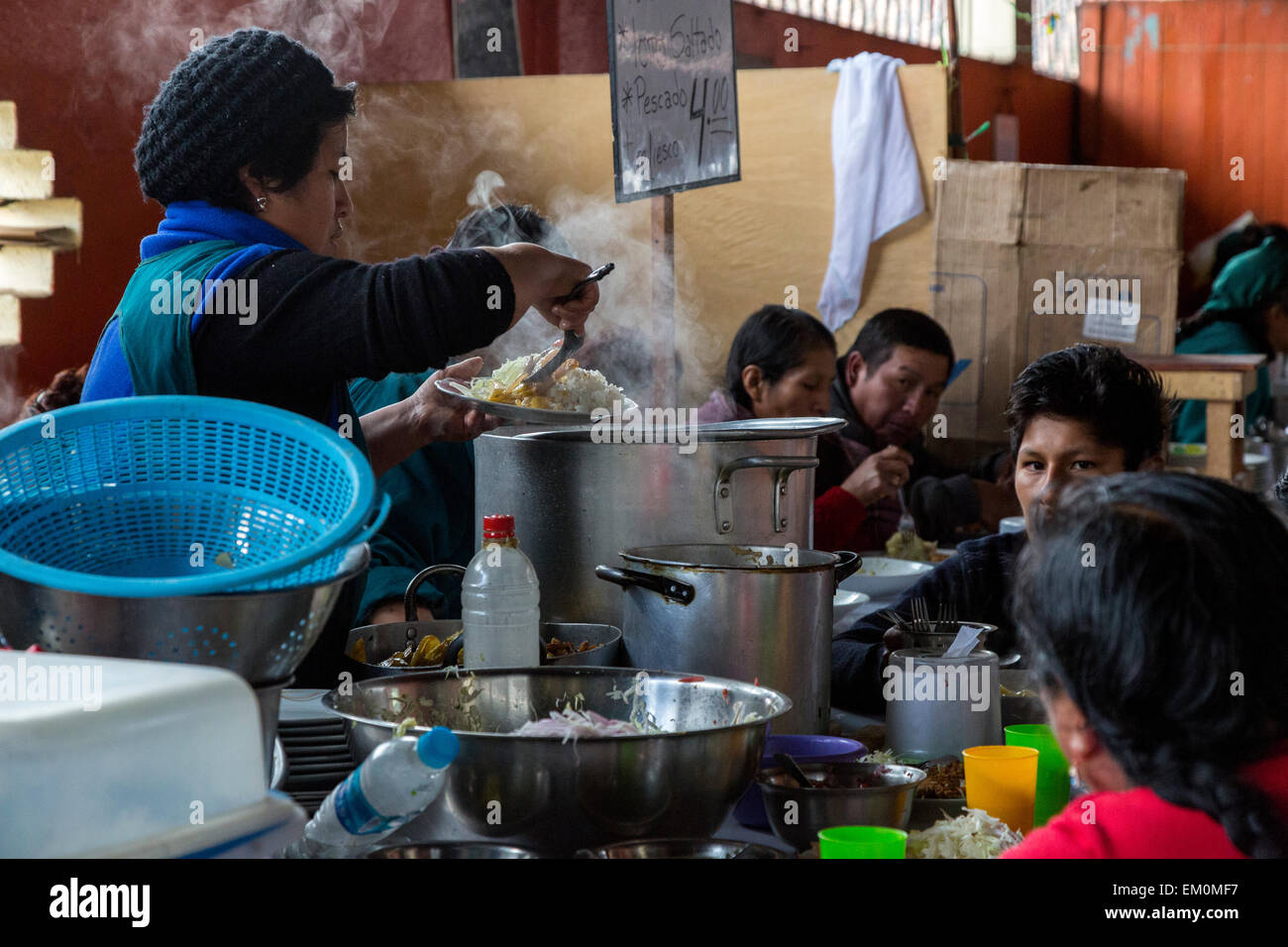 Perù Cusco, San Pedro mercato. Donna di incavature fino a che serve nel Food Court Area di mercato. Foto Stock