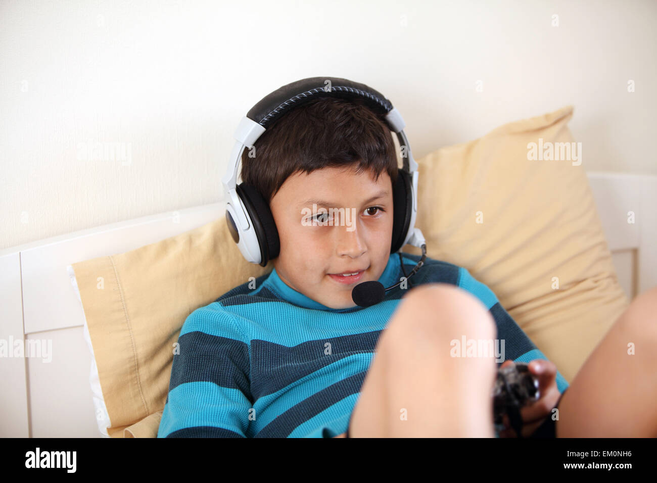 Giovane ragazzo sorridente la riproduzione del video gioco con i suoi amici con cuffia e microfono con spazio di copia Foto Stock