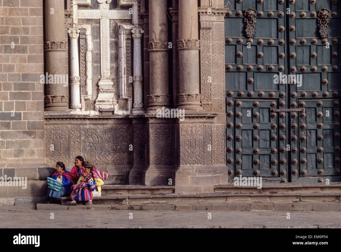 Perù Cusco. Tre donne quechua seduta dalla porta della chiesa, La Compania. Foto Stock