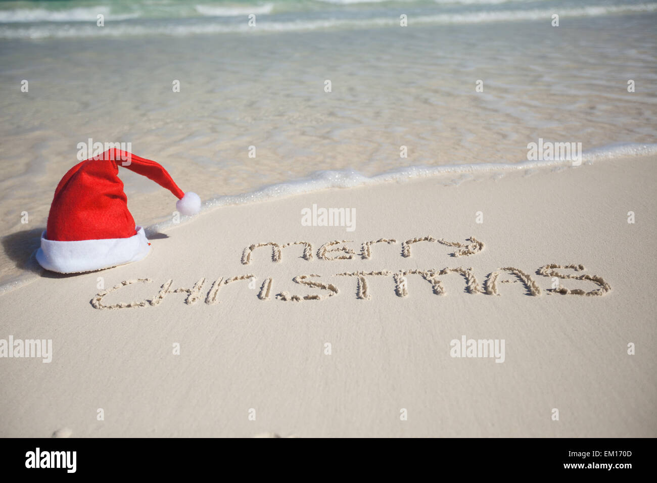 Buon Natale scritta sulla spiaggia tropicale di sabbia bianca con xmas hat Foto Stock