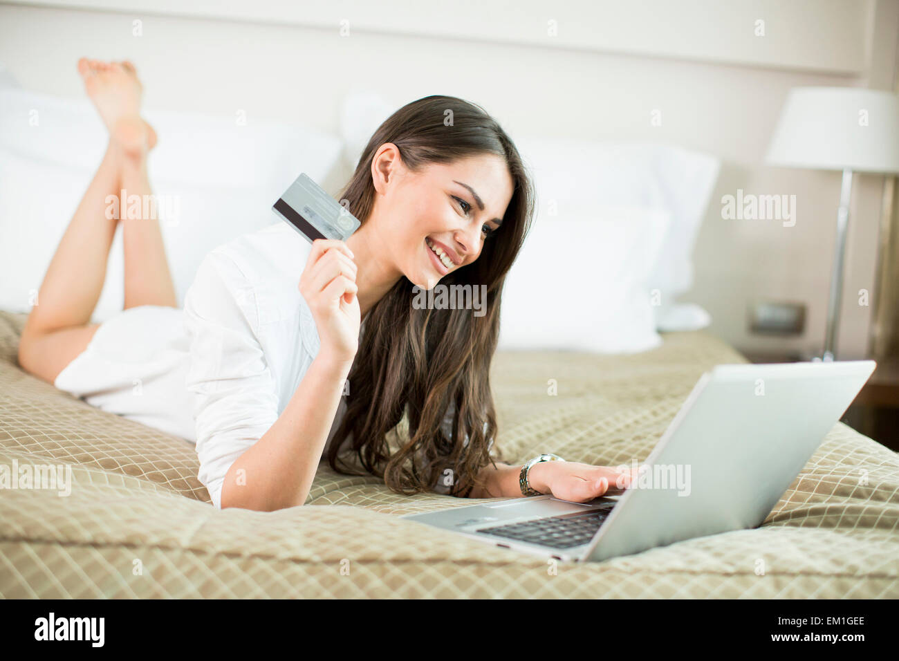 Giovane donna che stabilisce nel letto e lo shopping online Foto Stock
