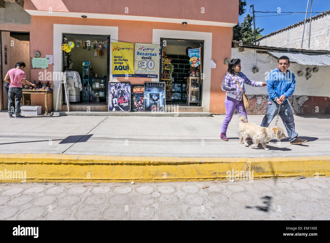 Coppia messicana a piedi soffici cane sul marciapiede provare a conversare come uomo lotte con guinzaglio per trattenere animale San Cristobal Foto Stock