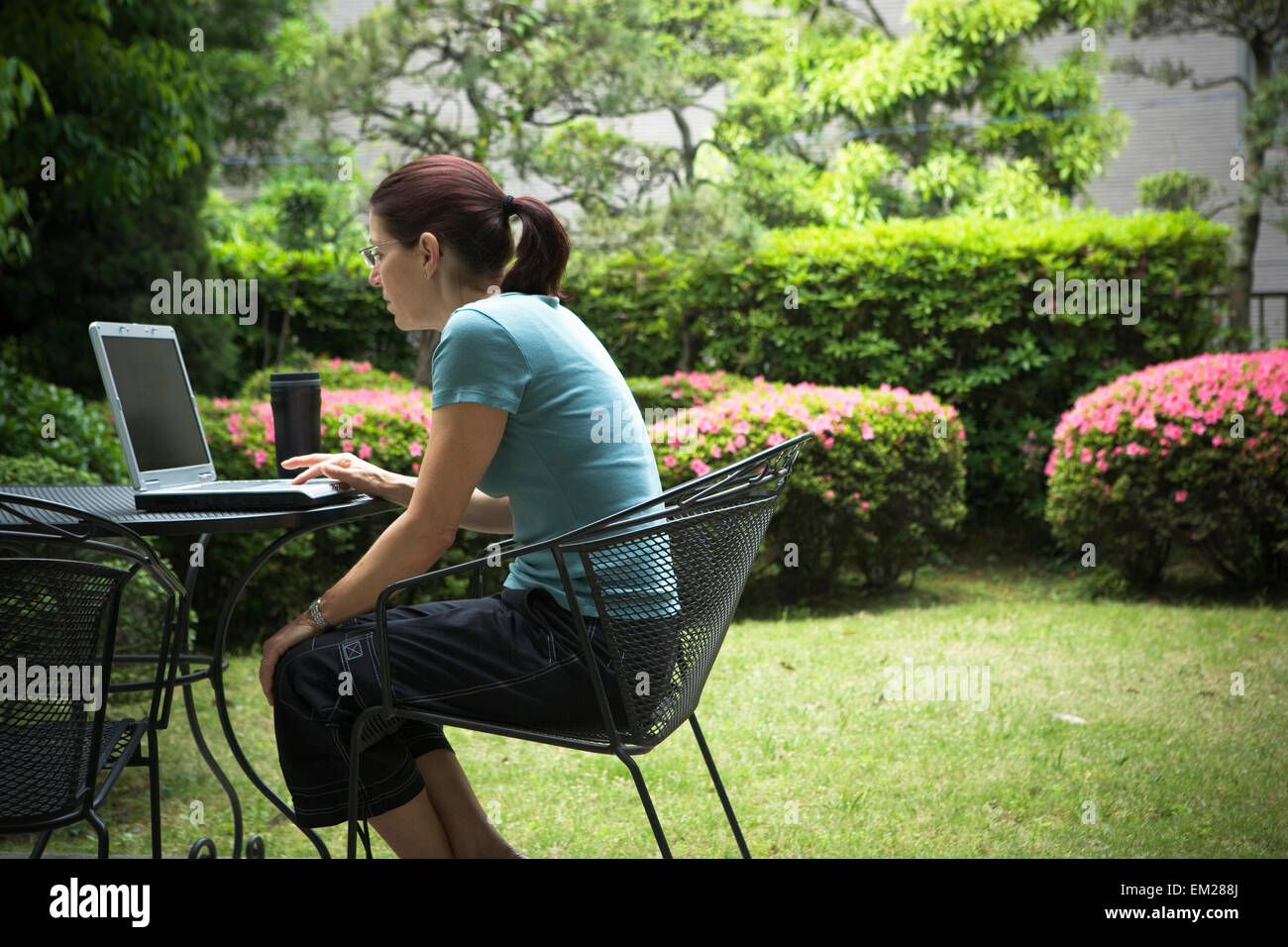 Una donna seduta davanti a un computer lap top all'esterno. Foto Stock