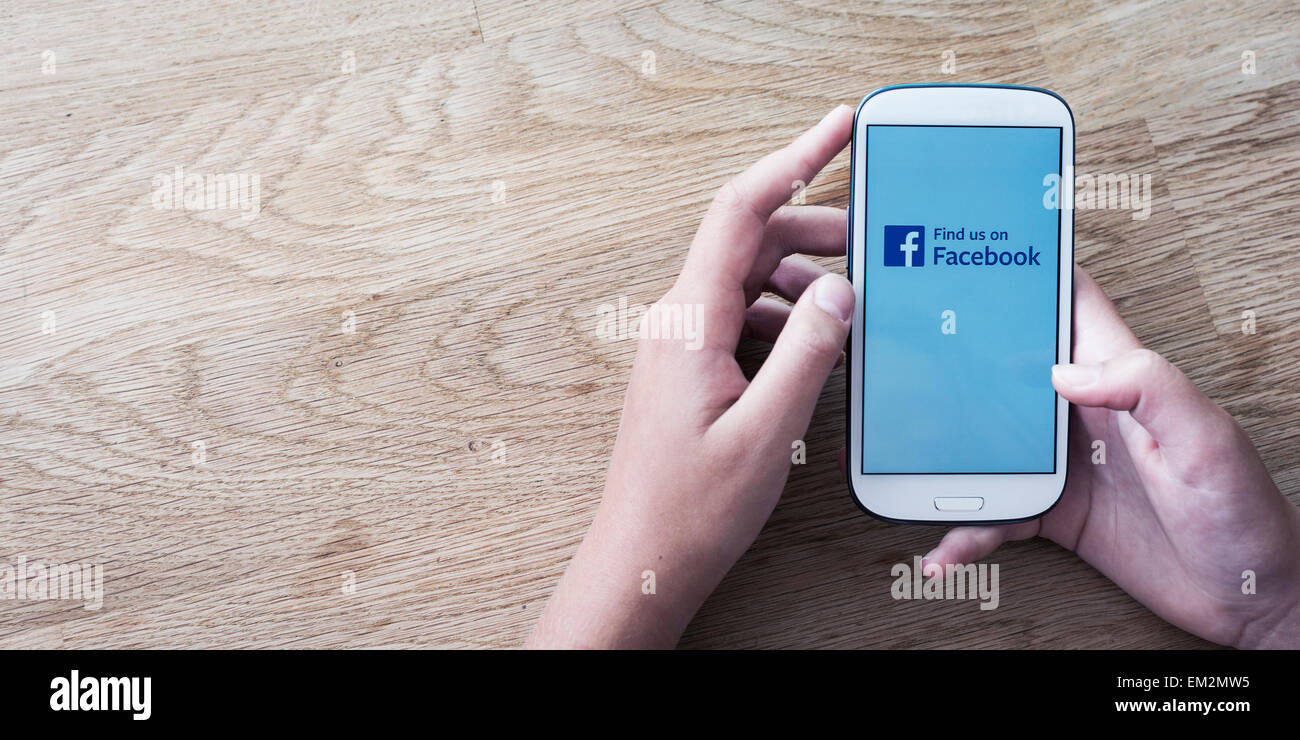 Mani tenendo il telefono cellulare con schermo di facebook o del logo Foto Stock