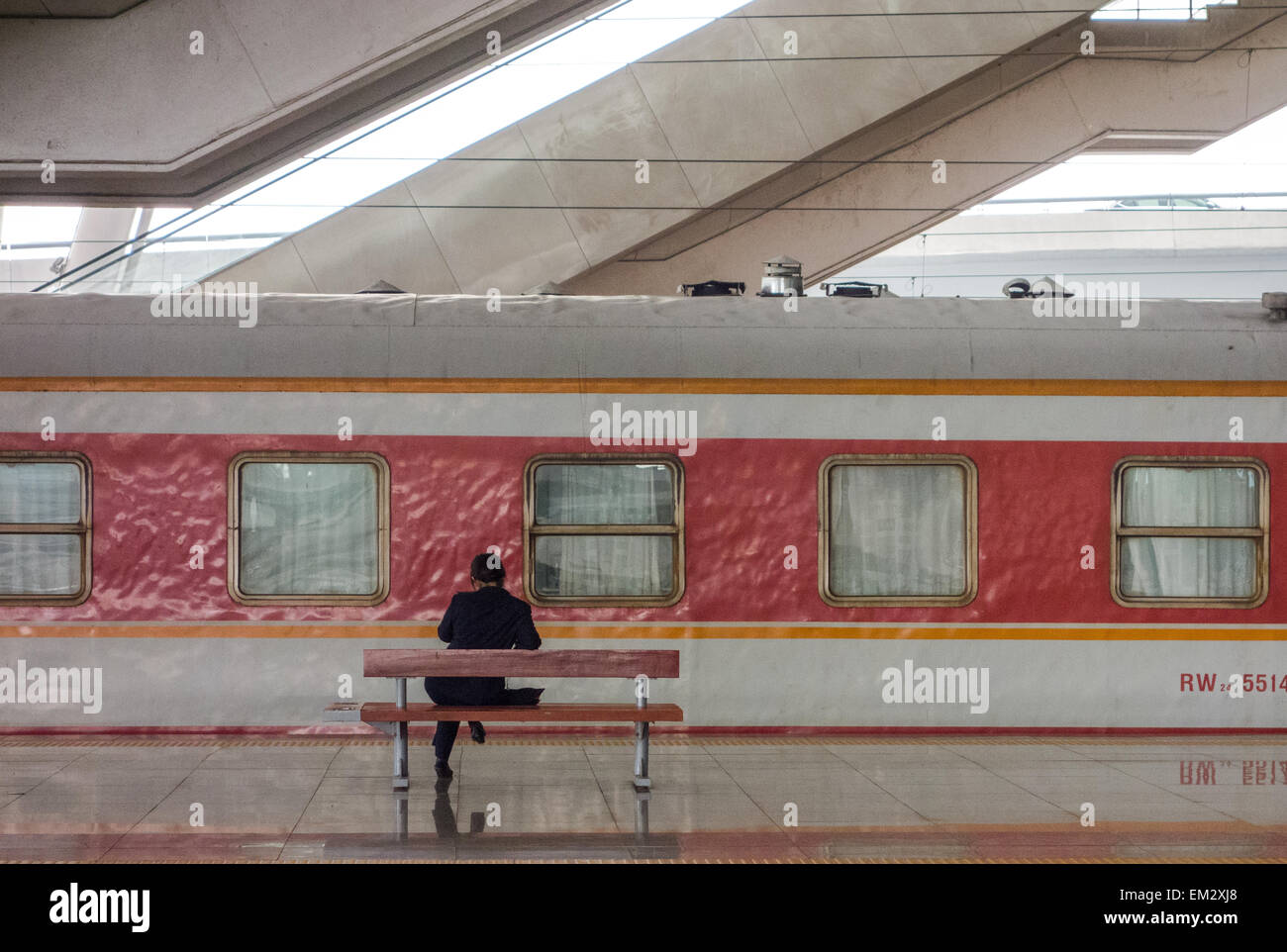 Un amministratore è in appoggio su una sedia sulla piattaforma mentre il treno ha una breve sosta nella stazione. Foto Stock