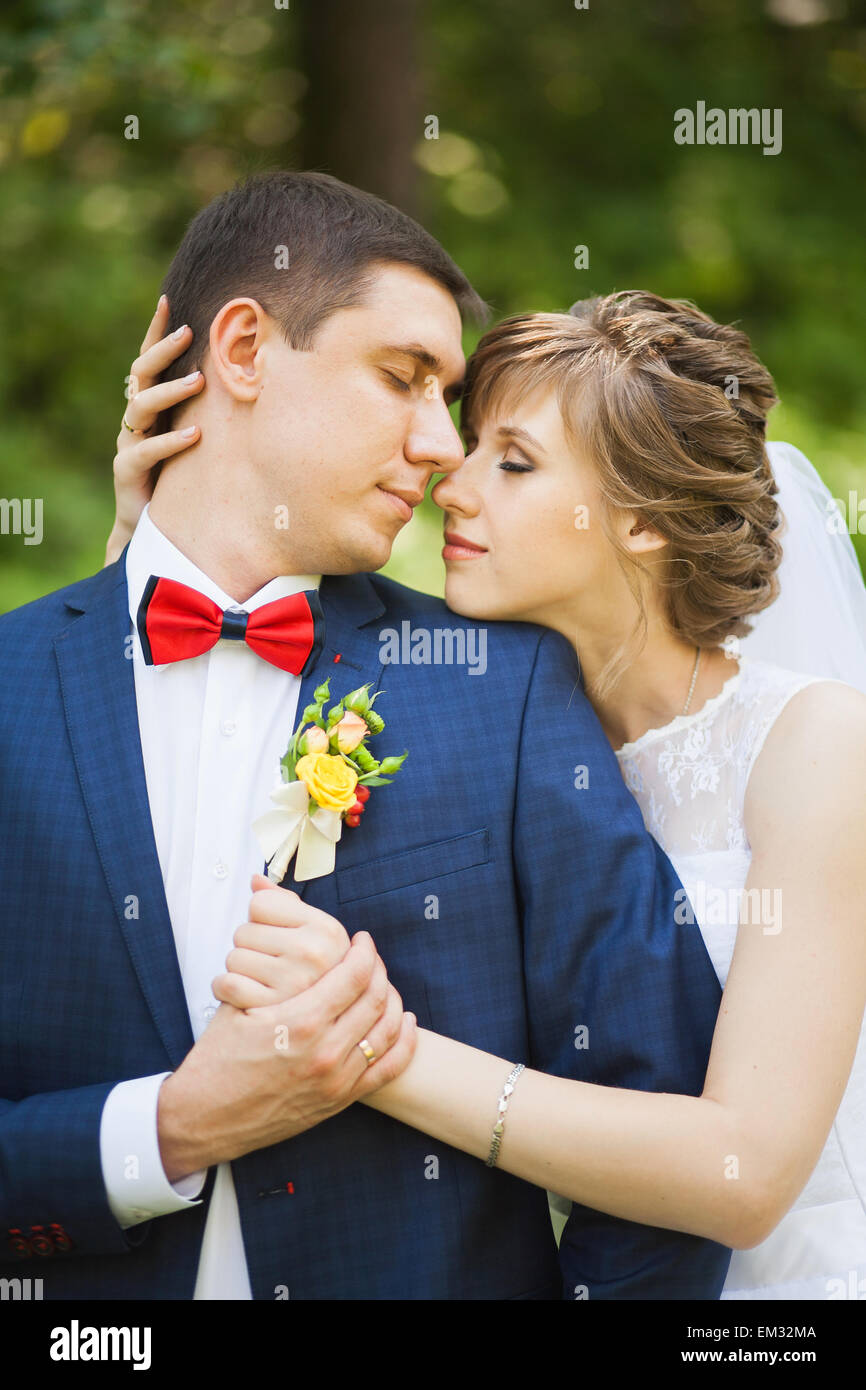 Felice sposa e lo sposo in piedi nel parco verde, baciare, sorridente, ridendo. close-up Foto Stock