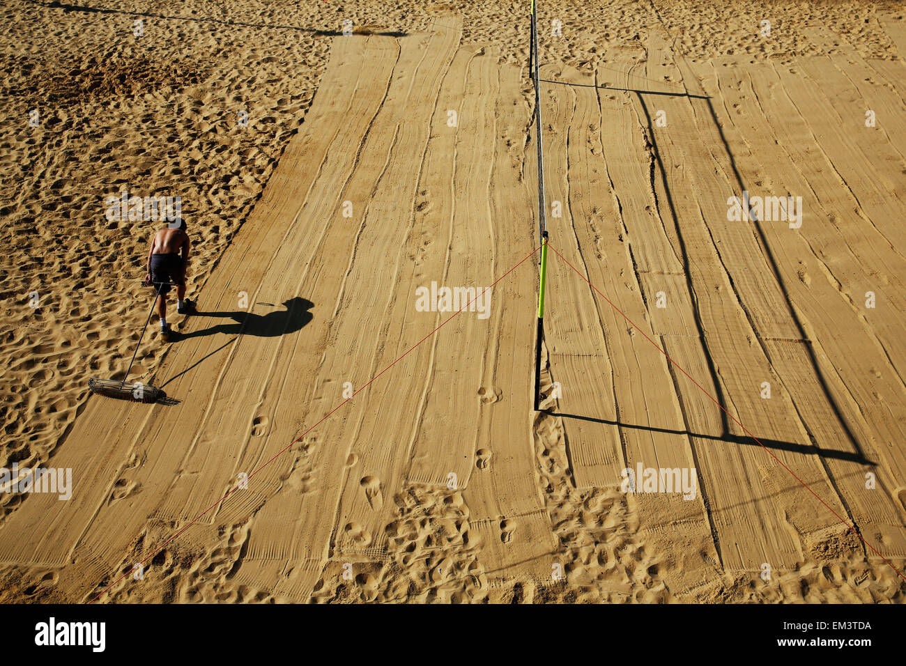 Un uomo smussa giù sabbia presso un campo da pallavolo su Brighton Seafront a Brighton in East Sussex Foto Stock