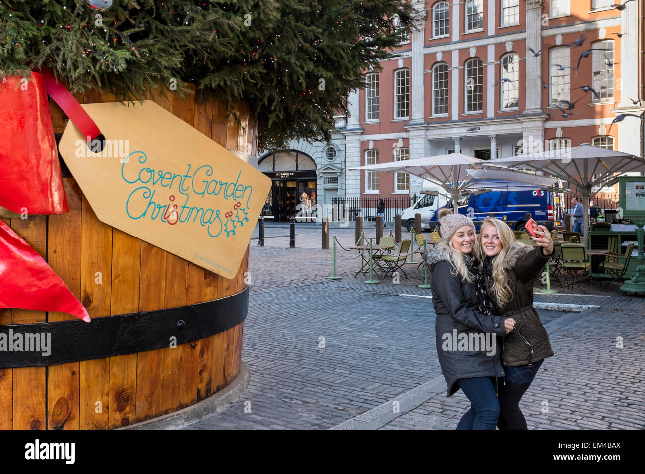 Due giovani donne che assumono selfies con il telefono cellulare e il Covent Garden di Londra, Regno Unito Foto Stock