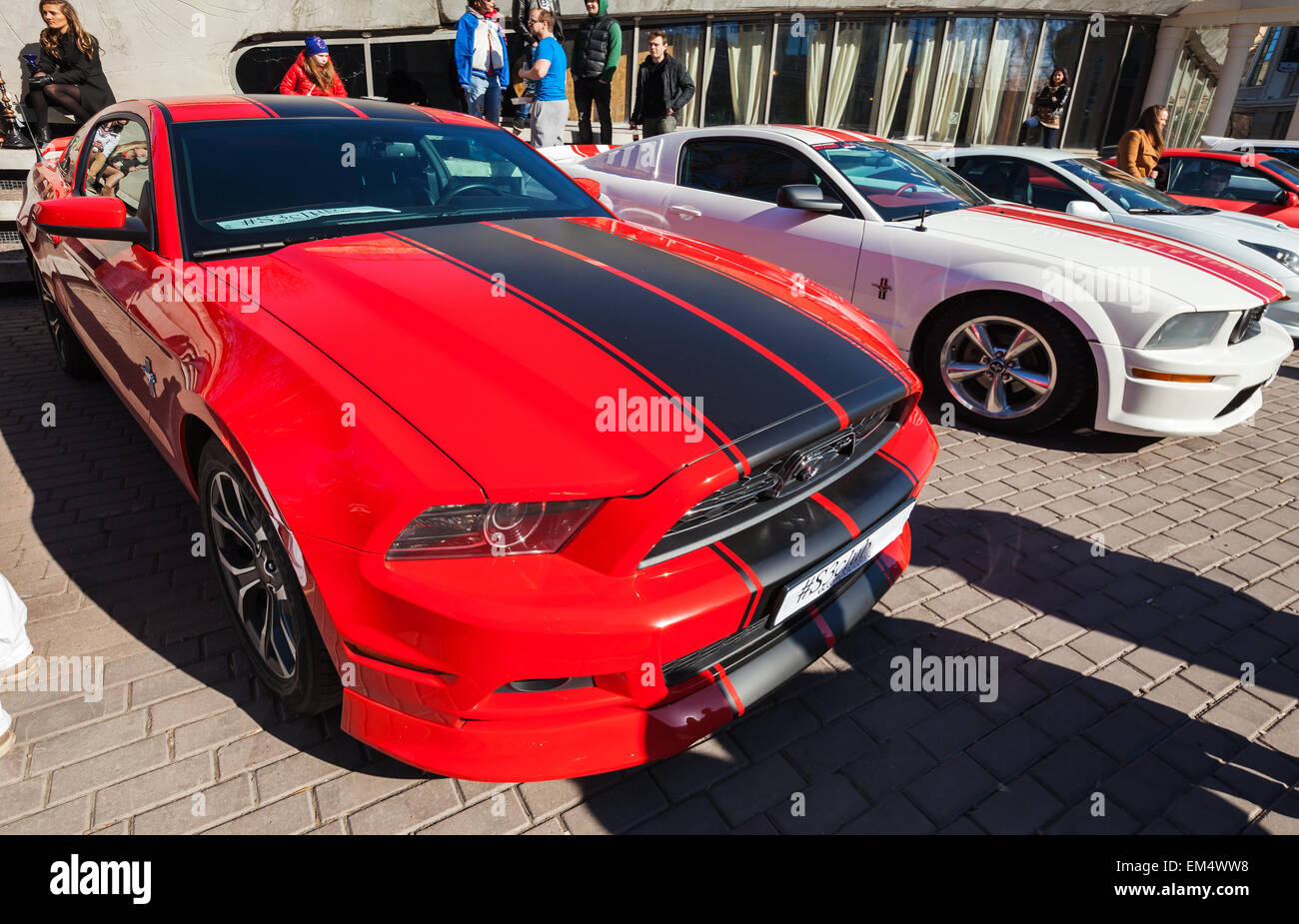 San Pietroburgo, Russia - 11 Aprile 2015: Rosso Ford Mustang con strisce nere si erge parcheggiato sulla strada di città Foto Stock