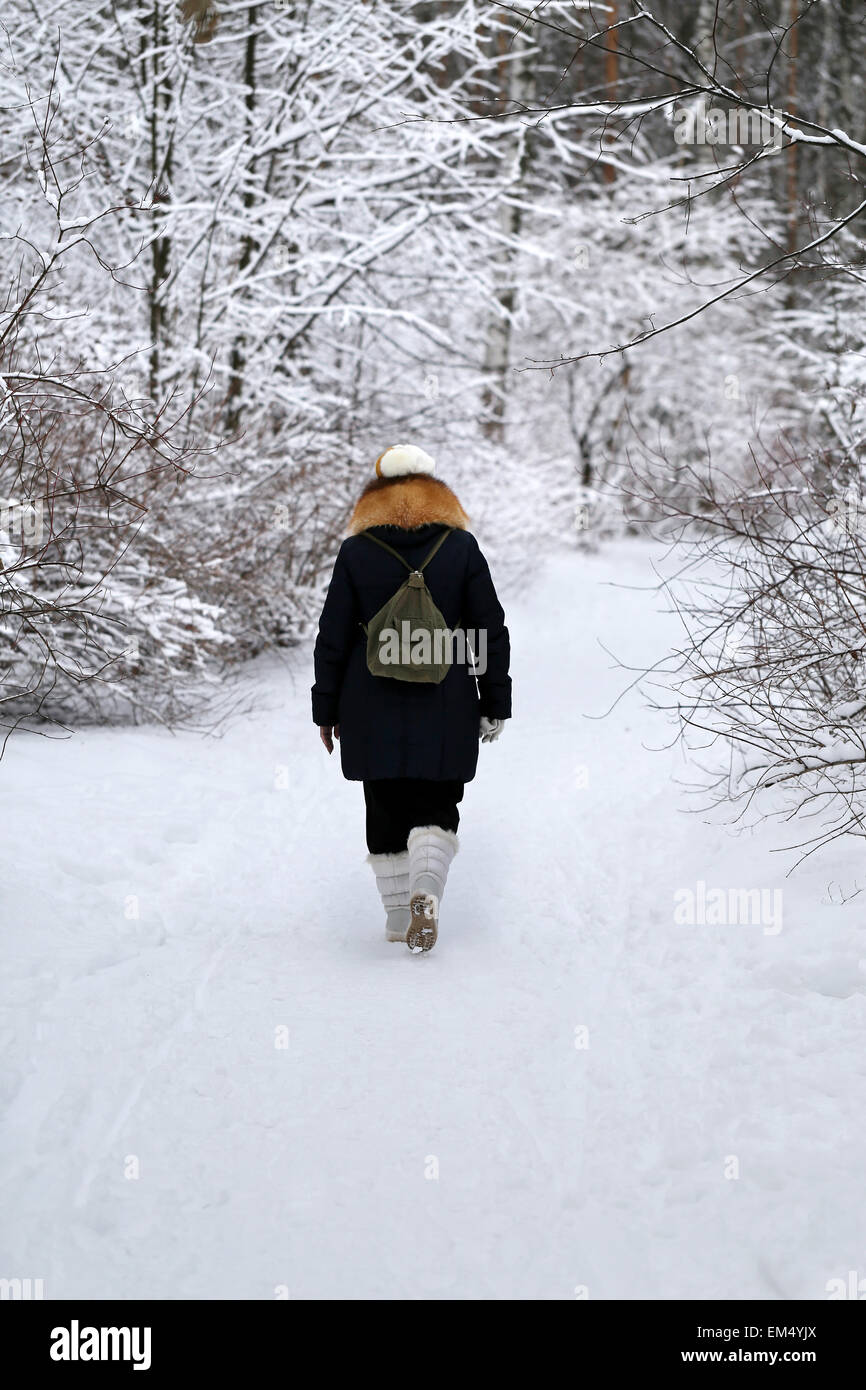 Donna cammina giù per un sentiero innevato in inverno forest Foto Stock