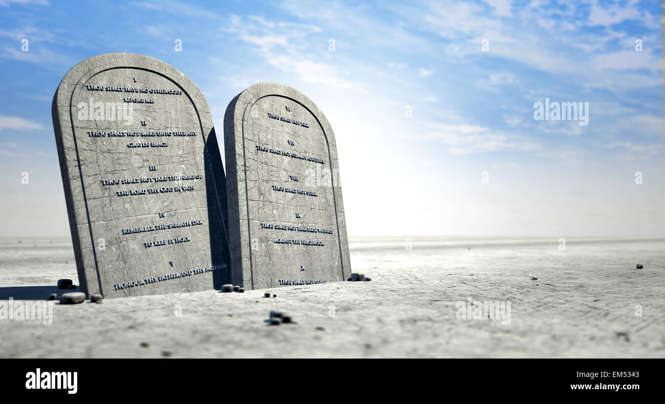 Due tavolette di pietra con i dieci comandamenti incisi su di loro in piedi in marrone sabbia del deserto di fronte un cielo blu Foto Stock