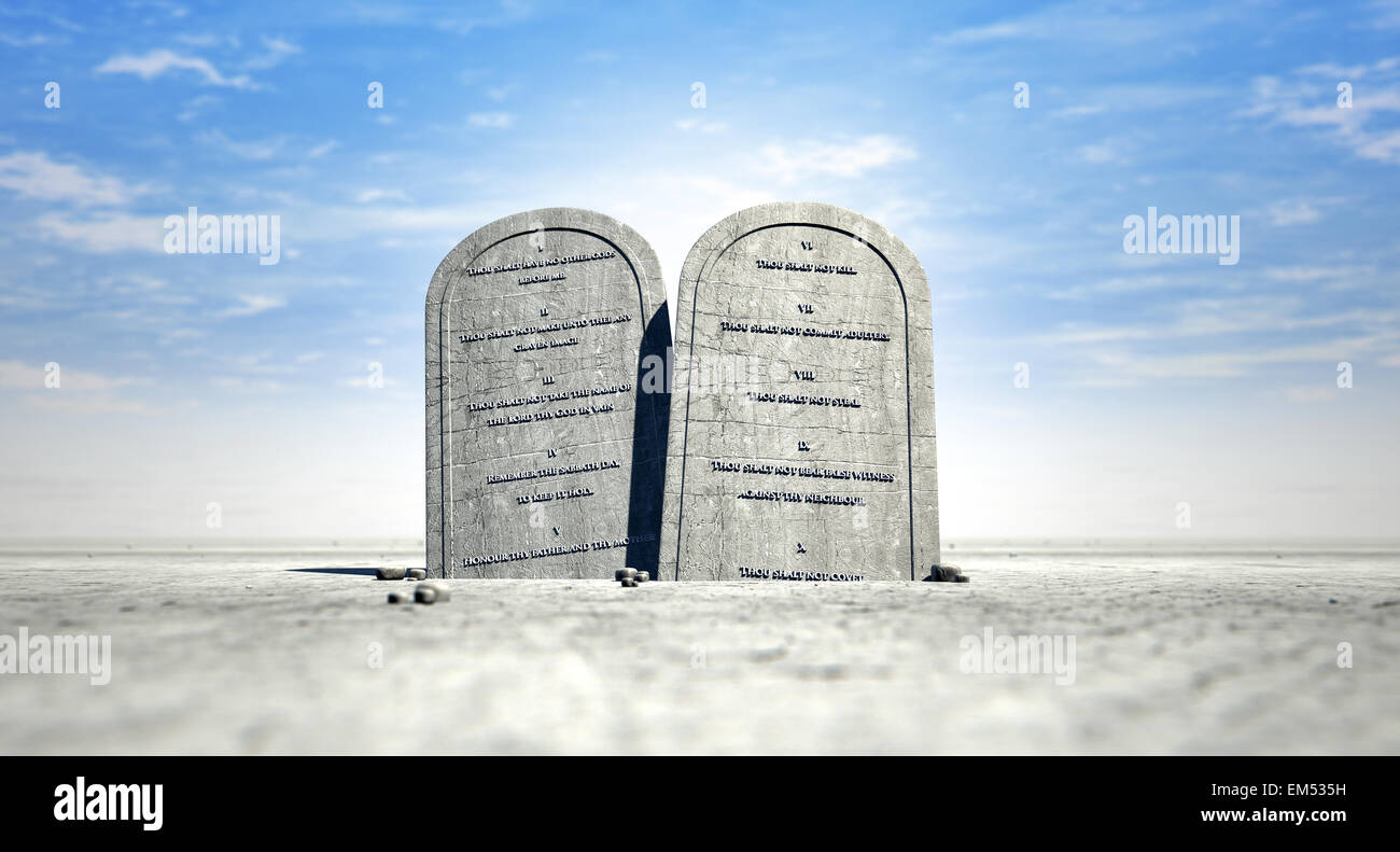 Due tavolette di pietra con i dieci comandamenti incisi su di loro in piedi in marrone sabbia del deserto di fronte un cielo blu Foto Stock