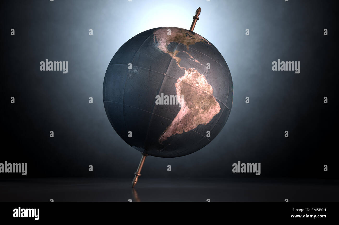 Un vintage Globo mondo inclinato e in piedi su un asse centrale su un isolato spotlit sfondo scuro Foto Stock