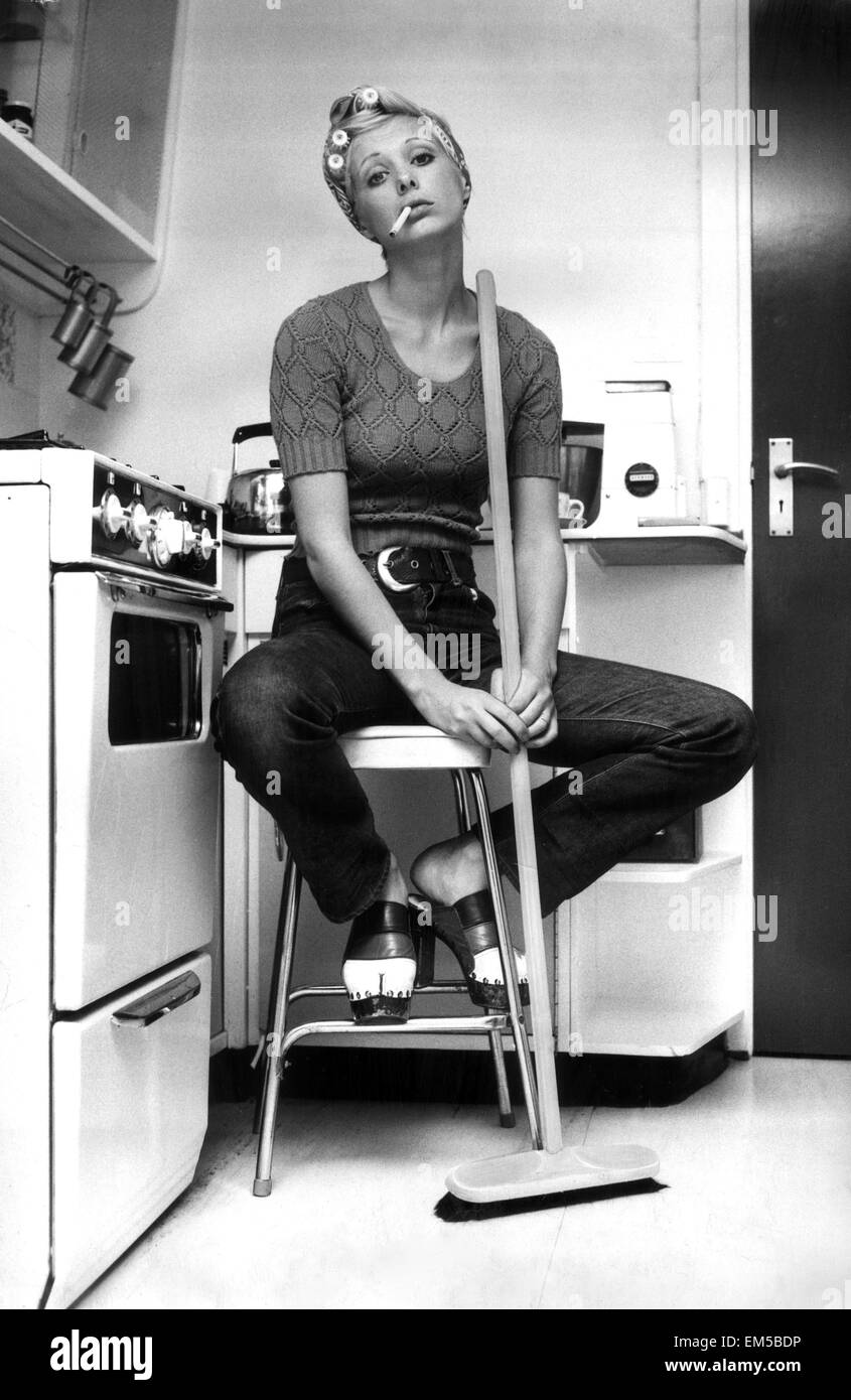 Modello di Nicki Howarth pone in cucina, tenendo in mano una scopa e fumare una sigaretta. Il 27 settembre 1972. Foto Stock