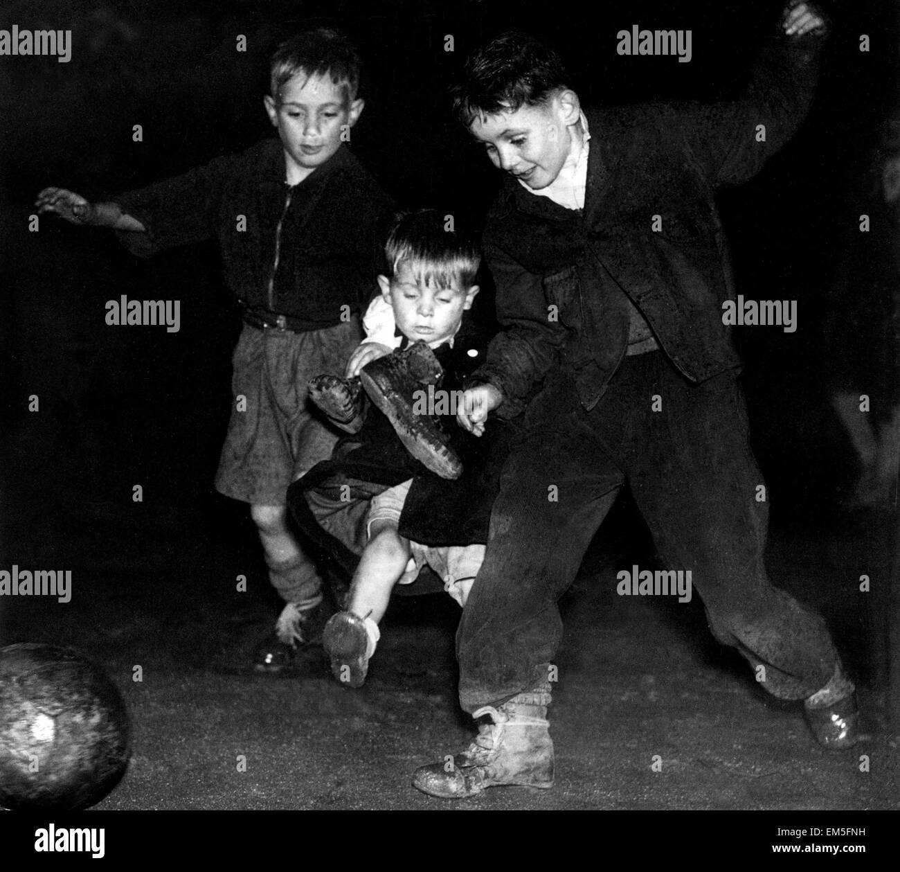 Proiettori di calcio per ragazzi. 3 fratelli competere per la palla. Il 3 ottobre 1950. Foto Stock