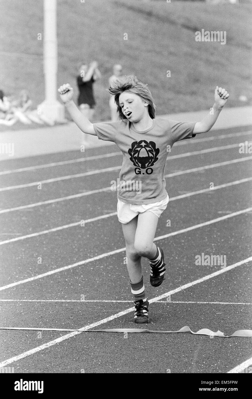 Un giovane ragazzo solleva le braccia nella celebrazione come egli attraversa la linea del traguardo per vincere la gara presso la loro scuola di sport al giorno. Xx Giugno 1979. Foto Stock