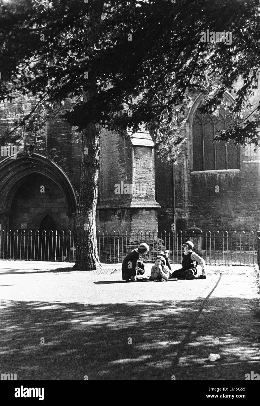 Infanzia confidenze nel parco giochi di ragazze scuola accanto alle mura di Tewesbury Abbazia nel Gloucestershire/ seduti all'ombra di alberi di circa 1935 Foto Stock