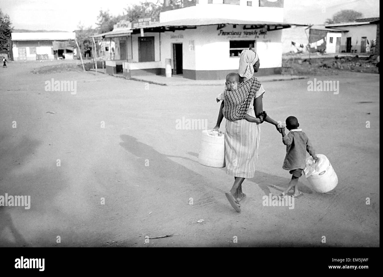 Una donna e un bambino che porta i bidoni di acqua e cercare il fiume. Ikutha, Kitui, Kenya. Le donne e i bambini sono quelli che Foto Stock