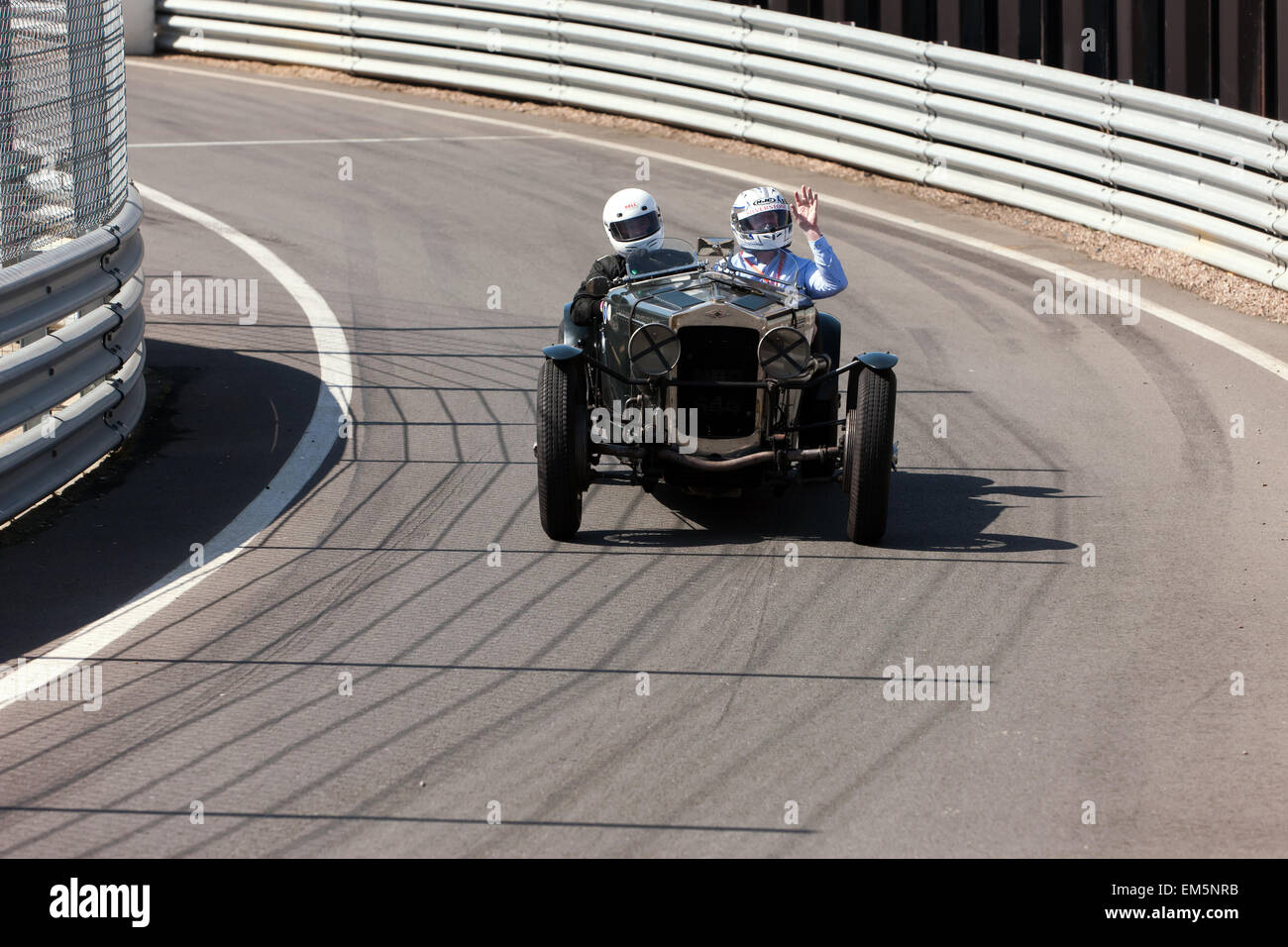 Un passeggero onde, come si gode il suo giro in un classico Frazer Nash race car. Conducente e passeggero sono uscendo dalla pit lane e costruzione di velocità, pronti a inserire la gara principale in pista a Silverstone. Foto Stock