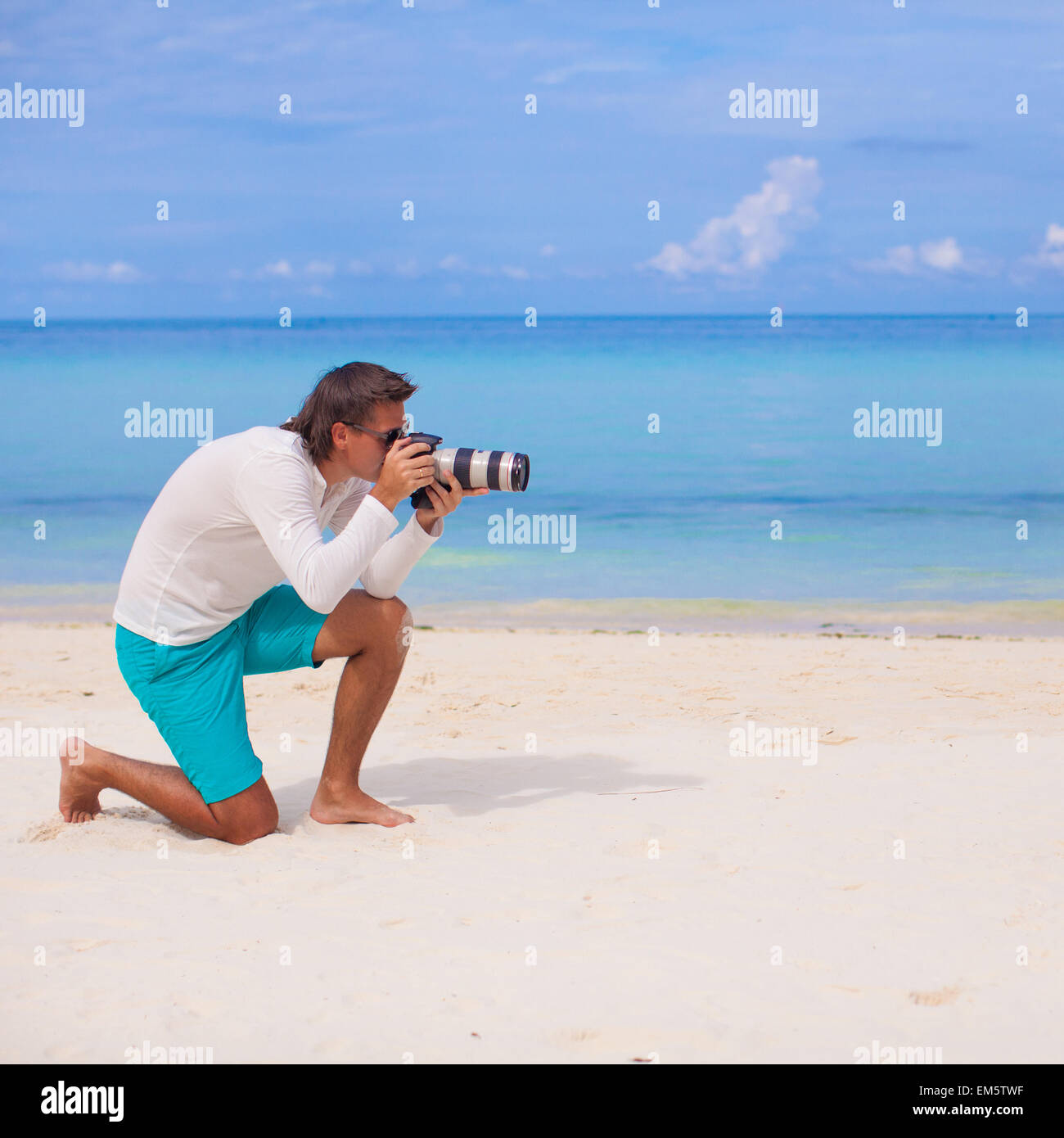 Profilo del giovane con la fotocamera in mano sulla bellissima spiaggia di sabbia bianca Foto Stock