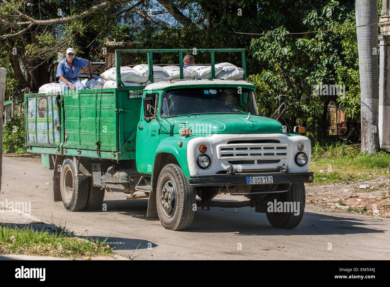 Uomo seduto su un vecchio carrello verde su una strada in una parte remota di Cuba Foto Stock