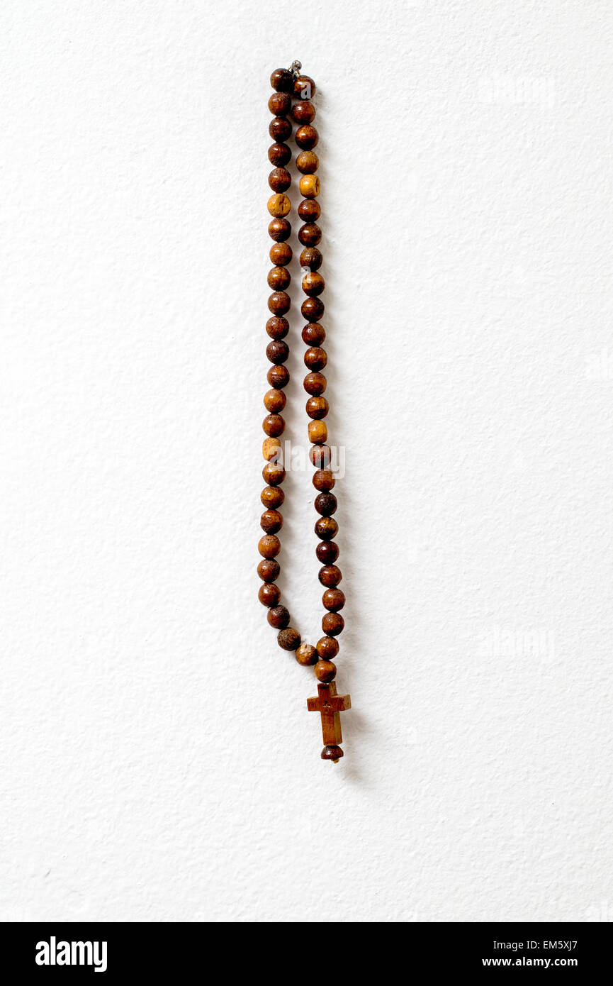 I grani del rosario appeso contro il muro bianco, close up Foto Stock