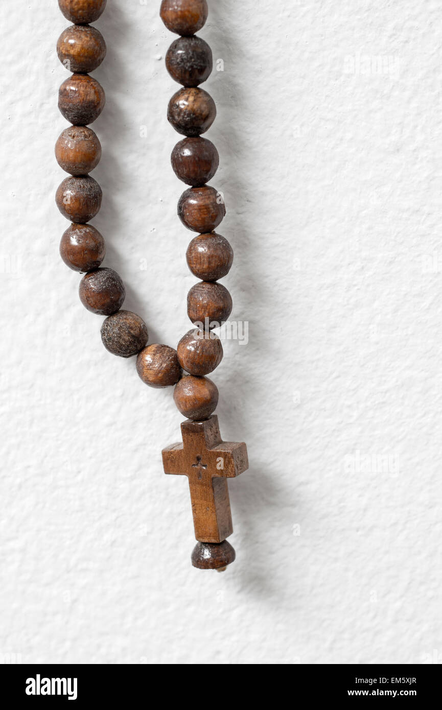 I grani del rosario appeso contro il muro bianco, close up Foto Stock