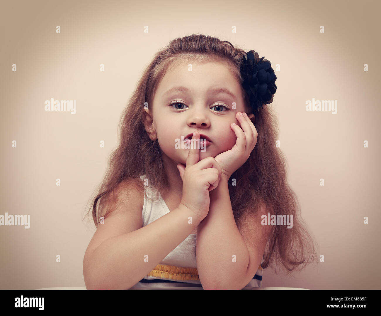 Carino kid ragazza che mostra il silenzio firmare il dito vicino le labbra. Vintage closeup ritratto Foto Stock