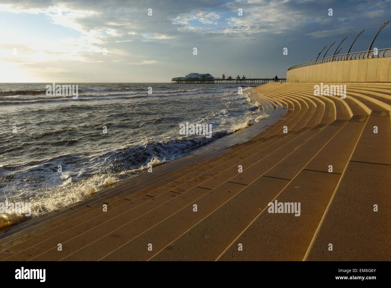 Promenade di Blackpool guardando in lontananza al molo con onde che lambiscono al prom Foto Stock