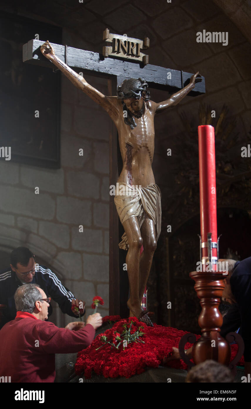 Due uomini decorano con garofani rossi un trono con la scultura di Gesù Cristo crocifisso durante la settimana Santa di pasqua nella Iglesia de Santiago Caceres, Estremadura, Spagna Foto Stock