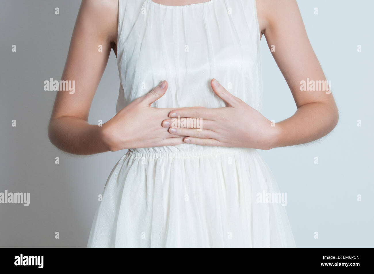 Chiudere fino a una giovane donna le mani sulla pancia Foto Stock