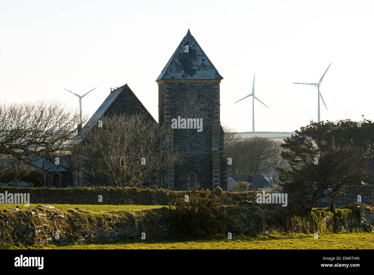 Chiesa in Delabole, Cornwall Regno Unito, è backdropped da energia eolica turbine. Foto Stock