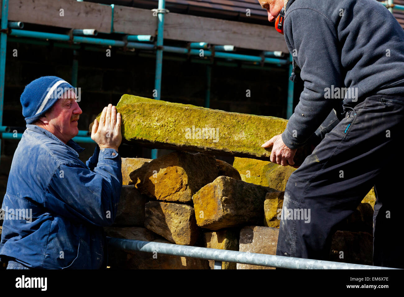 Costruttori lavora in un cantiere con i ponteggi pali in pietra e mattoni a vista Foto Stock