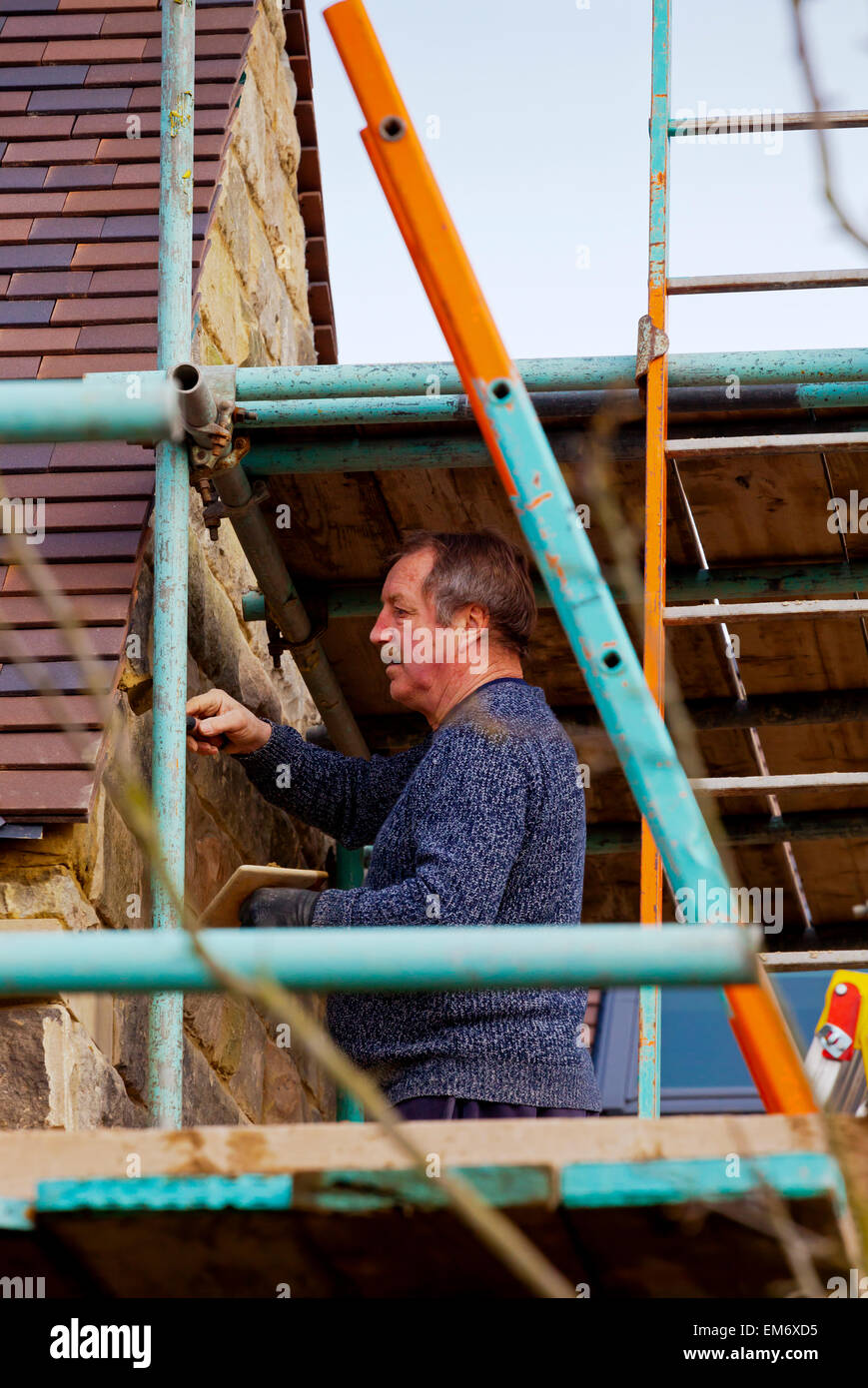 Costruttori lavora in un cantiere con i ponteggi pali in pietra e mattoni a vista Foto Stock