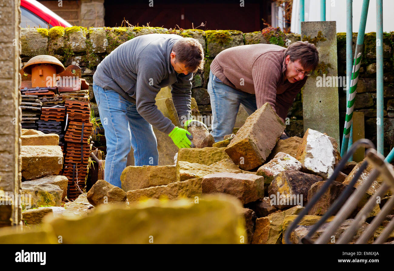 Costruttori lavora in un cantiere con i ponteggi pali in pietra e mattoni a vista Foto Stock