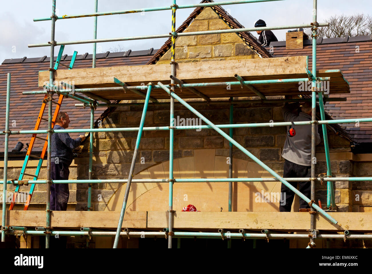 Costruttori lavora in un cantiere con i ponteggi pali in pietra e mattoni a vista Foto Stock