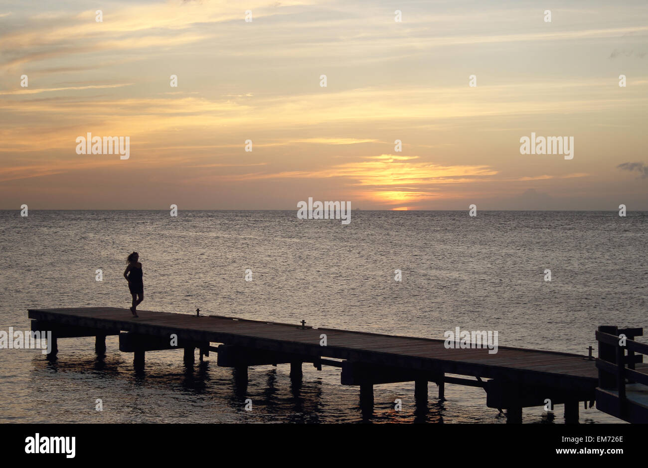 Donna che cammina lungo dopo un bellissimo tramonto su un resort dock a Curacao nelle Antille olandesi. Foto Stock