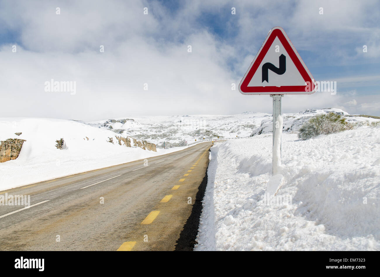 Curve pericolose segno su una strada di montagna. Foto Stock