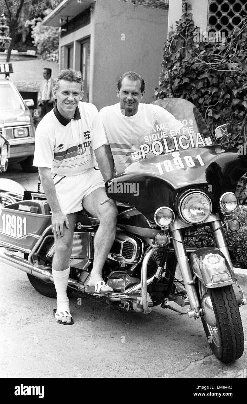 Calciatore inglese Peter Reid bendato con la gamba destra in seguito ad una lesione, seduto su di una polizia messicana motociclo con il compagno di squadra Ray Wilkins presso la base del team a Monterrey in Messico prima del 1986 World Cup torneo. Maggio 1986. Foto Stock