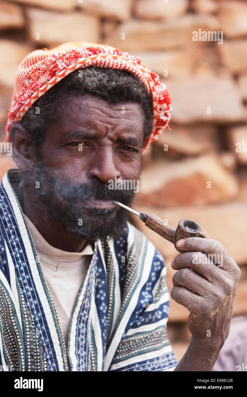 Ritratto di un uomo Dogon fumare una tubazione in Tireli, Mali Foto Stock