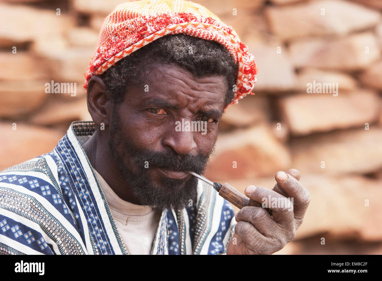 Ritratto di un uomo Dogon fumare una tubazione in Tireli, Mali Foto Stock
